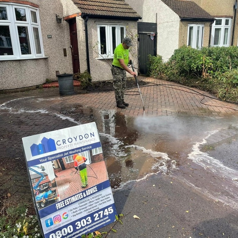 Worker jet washing driveway